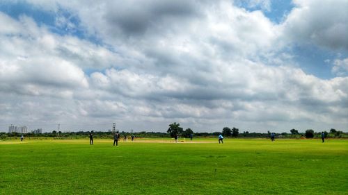 People playing on field against sky