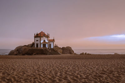 Church by sea against sky during sunset