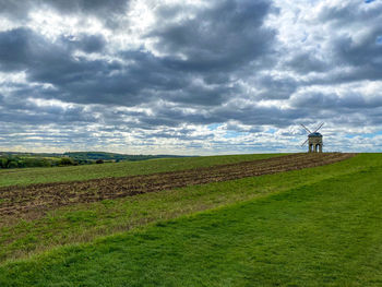 Scenic view of windmill in a field against cloudy sky