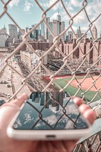 View of cityscape through chainlink fence