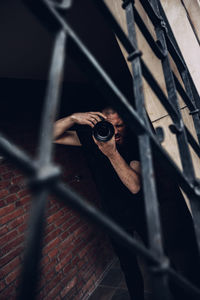 Close-up of person holding metal fence against blurred background