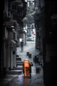 Rear view of worker walking under rain on street