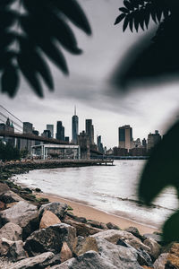 View of buildings by river against cloudy sky