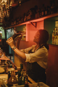Smiling female bartender preparing cocktail while working at bar counter