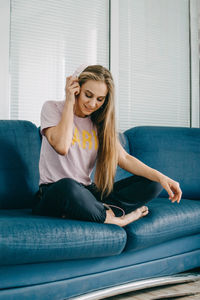 Young woman sitting on sofa at home