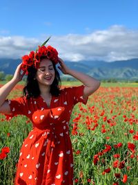 Woman standing by red poppy flowers in field