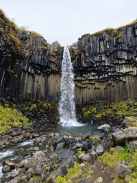 Scenic view of waterfall in forest cliff rock mountain view water green iceland holiday travel