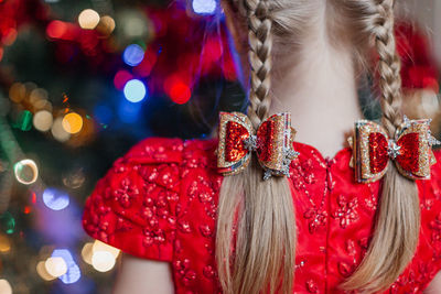 Christmas bows on the head of a girl standing next to the christmas tree