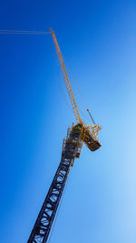 Low angle view of crane against clear blue sky