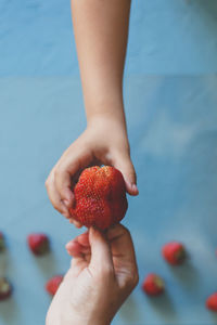 Directly above shot of cropped hands holding strawberry at home
