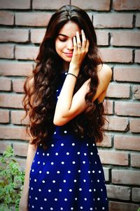 Young woman standing against brick wall