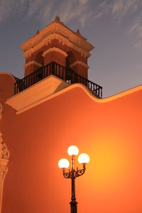 Low angle view of illuminated building against sky during sunset