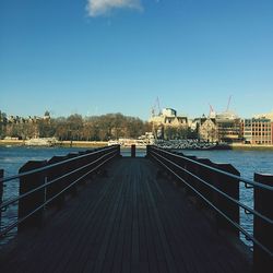 Pier over river in city against sky