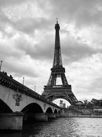 Arch bridge over river against cloudy sky