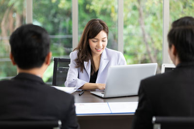 Colleagues sitting on table at office