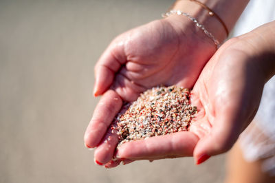 Cropped hand of woman holding pink sand of elafonisi beach in crete, greece