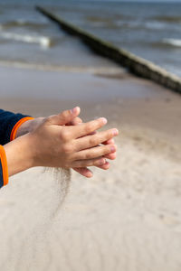 Cropped hands with sands at beach