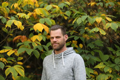 Portrait of man standing against leaves