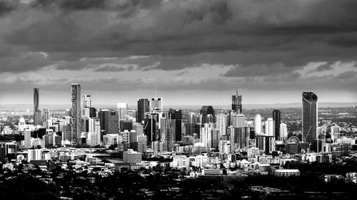 Aerial view of buildings in city against cloudy sky