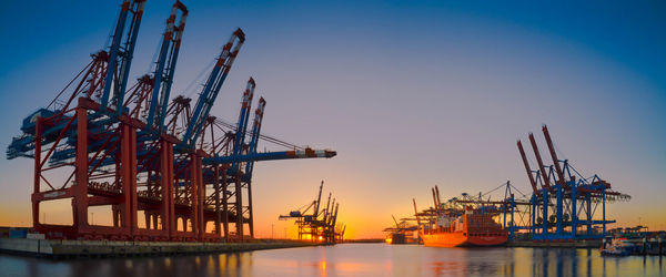 Harbor at sea against sky during sunset