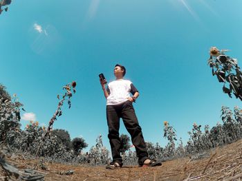 Low angle view of man standing against blue sky