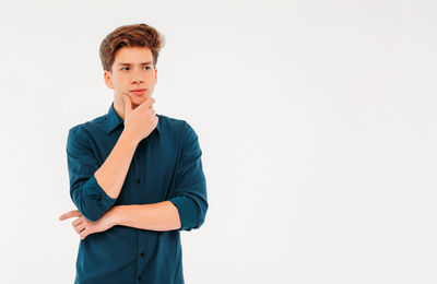 Portrait of young man standing against white background