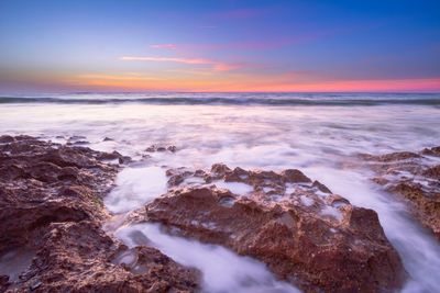 Frozen sea against sky during sunset