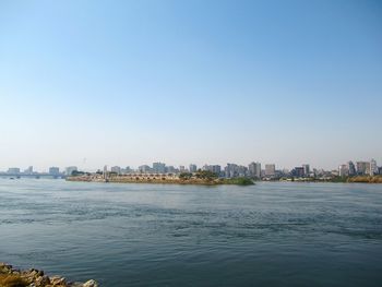 Sea by buildings against clear blue sky