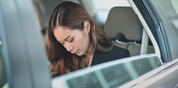 Portrait of young woman looking through window