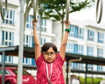 Young asian children hang on the monkey bar. to exercise at outdoor playground in the neighbourhood.