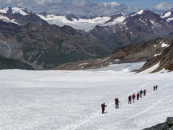 People on snowcapped mountains against sky