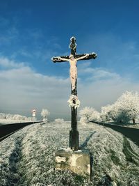 Statue of cross against sky