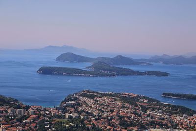 Scenic view of sea by city against sky during sunset