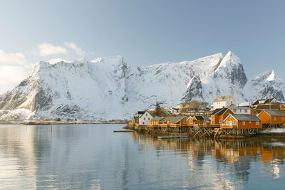 Stilt houses by lake against snowcapped mountains