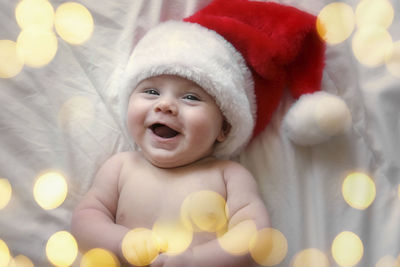 Smiling baby wearing red santa claus hat celebrating christmas. cute newborn baby in christmas hat