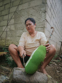 Midsection of a man holding woman sitting against wall