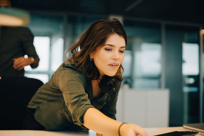 Confident businesswoman working at desk in creative office