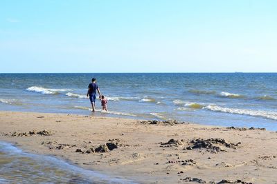 People on beach against clear sky