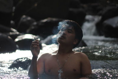Portrait of shirtless young woman sitting outdoors