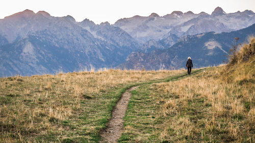 Hiker walking on pathway amidst mountains
