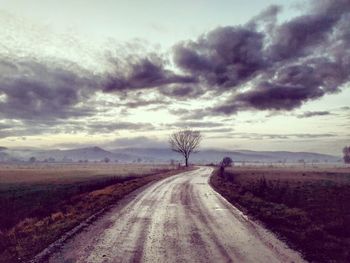 Road amidst field against sky