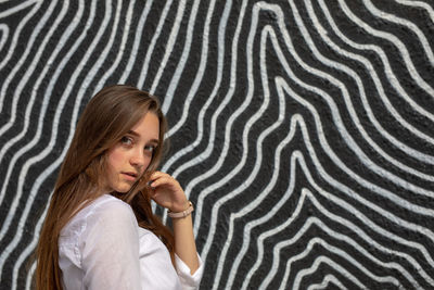 Portrait of young woman standing against graffiti wall