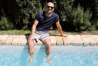 Portrait of young man sitting in swimming pool