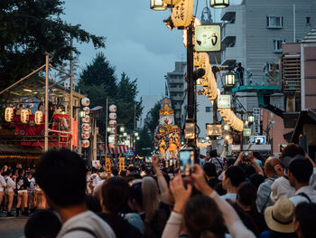 People on street against buildings in city