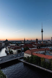 Bridge over river by buildings in city against sky