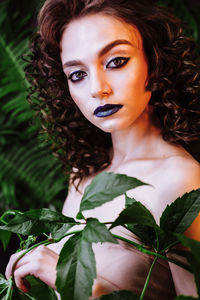 Portrait of beautiful redhead woman wearing make-up by plants