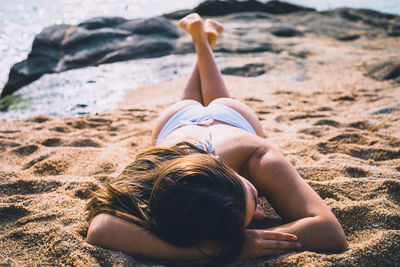 Midsection of woman lying down on sand at beach