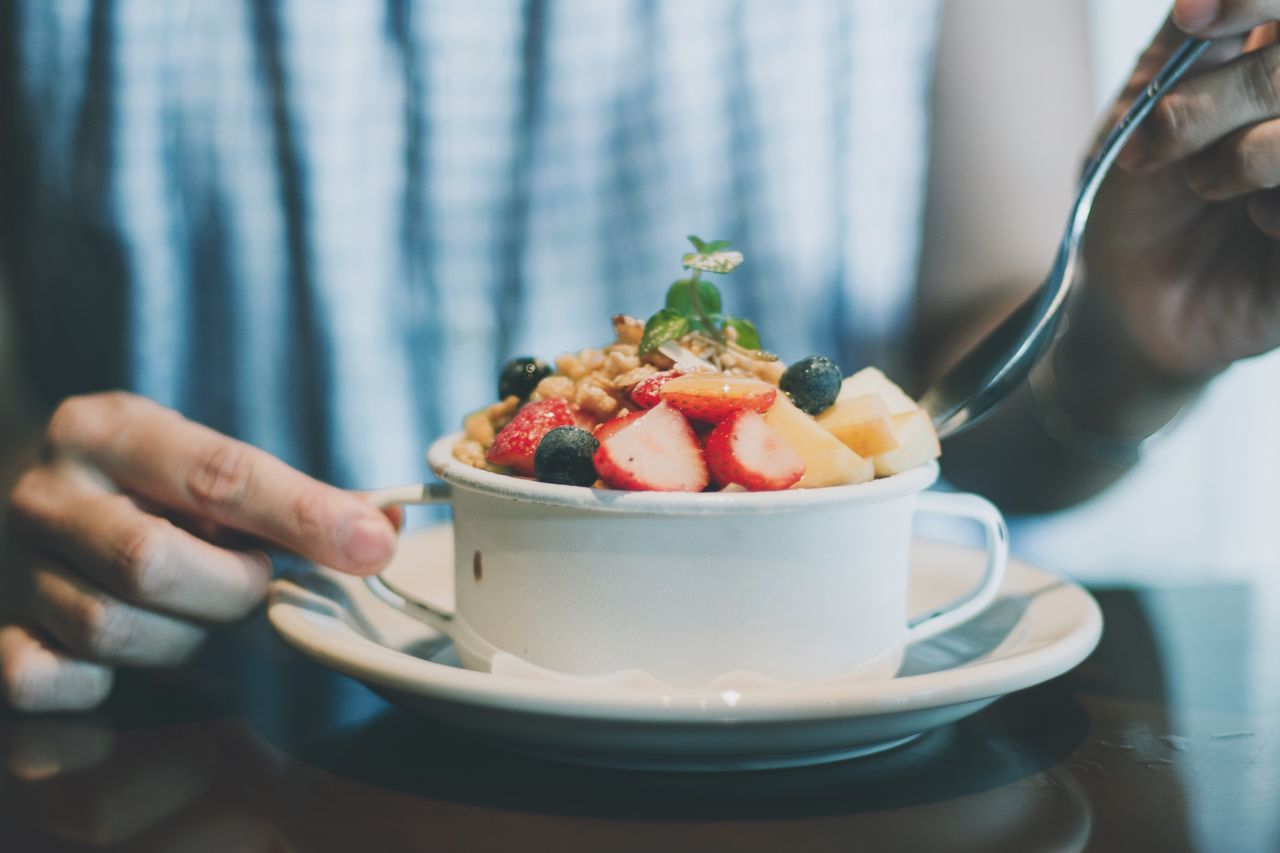 food, food and drink, berry fruit, freshness, one person, healthy eating, fruit, strawberry, bowl, lifestyles, real people, kitchen utensil, wellbeing, indoors, midsection, holding, human hand, table, eating utensil, hand