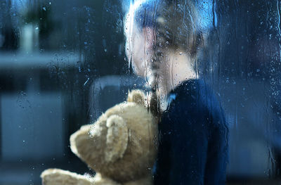 Portrait of woman seen through wet glass window