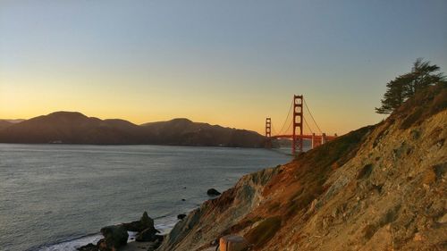 Suspension bridge over sea against clear sky